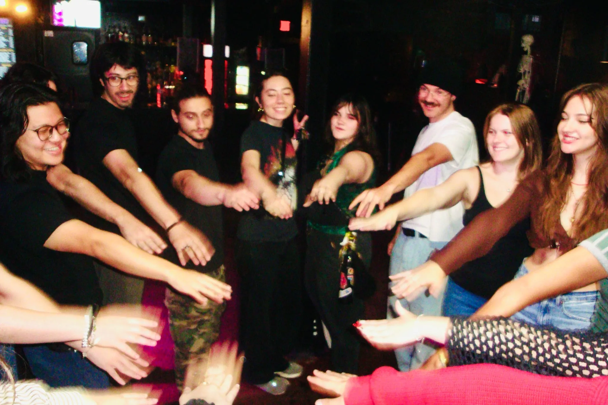The crew standing in a circle with their hands in the middle.